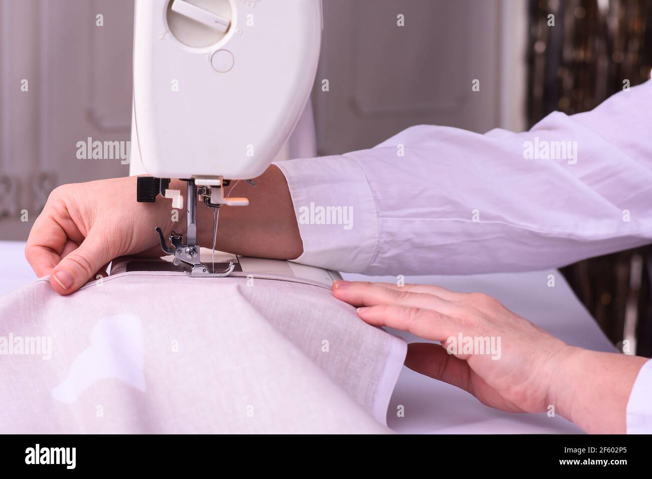 the dressmaker stitches the fabric on a sewing machine.  Stock Photo