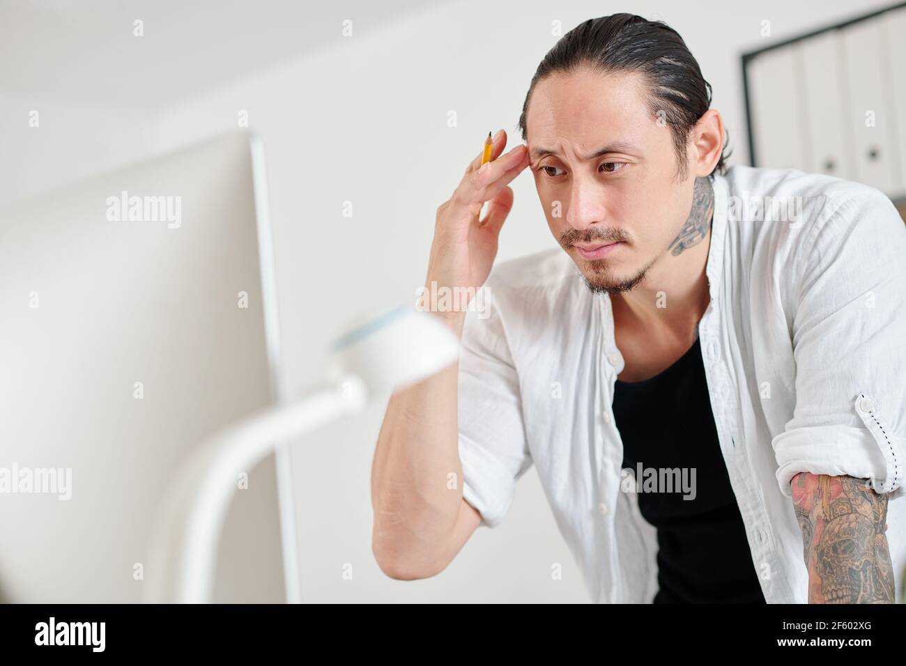 Frowning serious graphic designer reading e-mail from client on computer screen Stock Photo