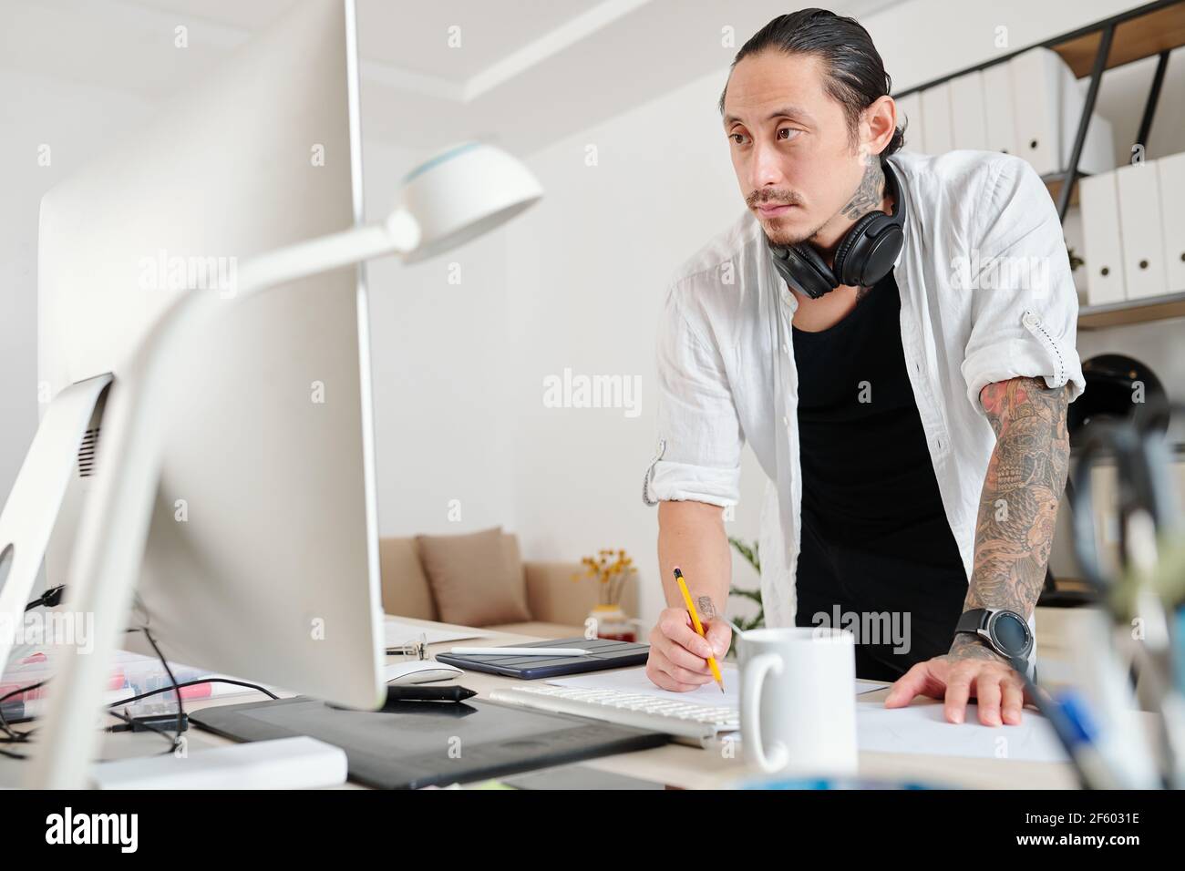 Pensive designer reading e-mail from client when drawing logotype for a big company Stock Photo