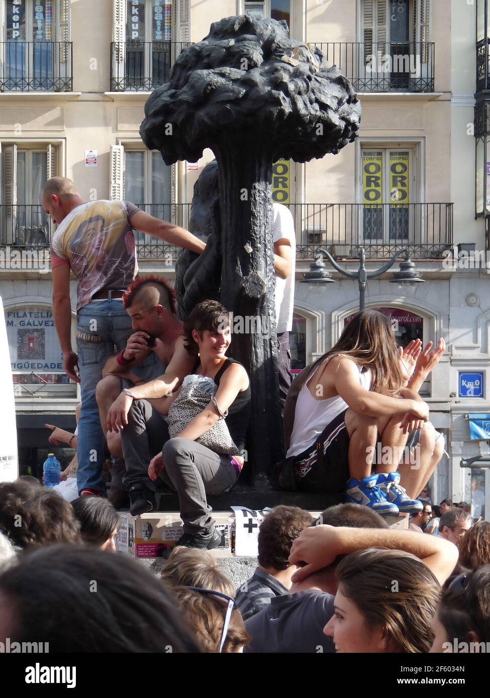 Madrid, Spain; June 11 2011. People on the statue of Oso y el Madroño watching. 15-M Indignados protests and encampment at Puerta del Sol in Madrid. P Stock Photo