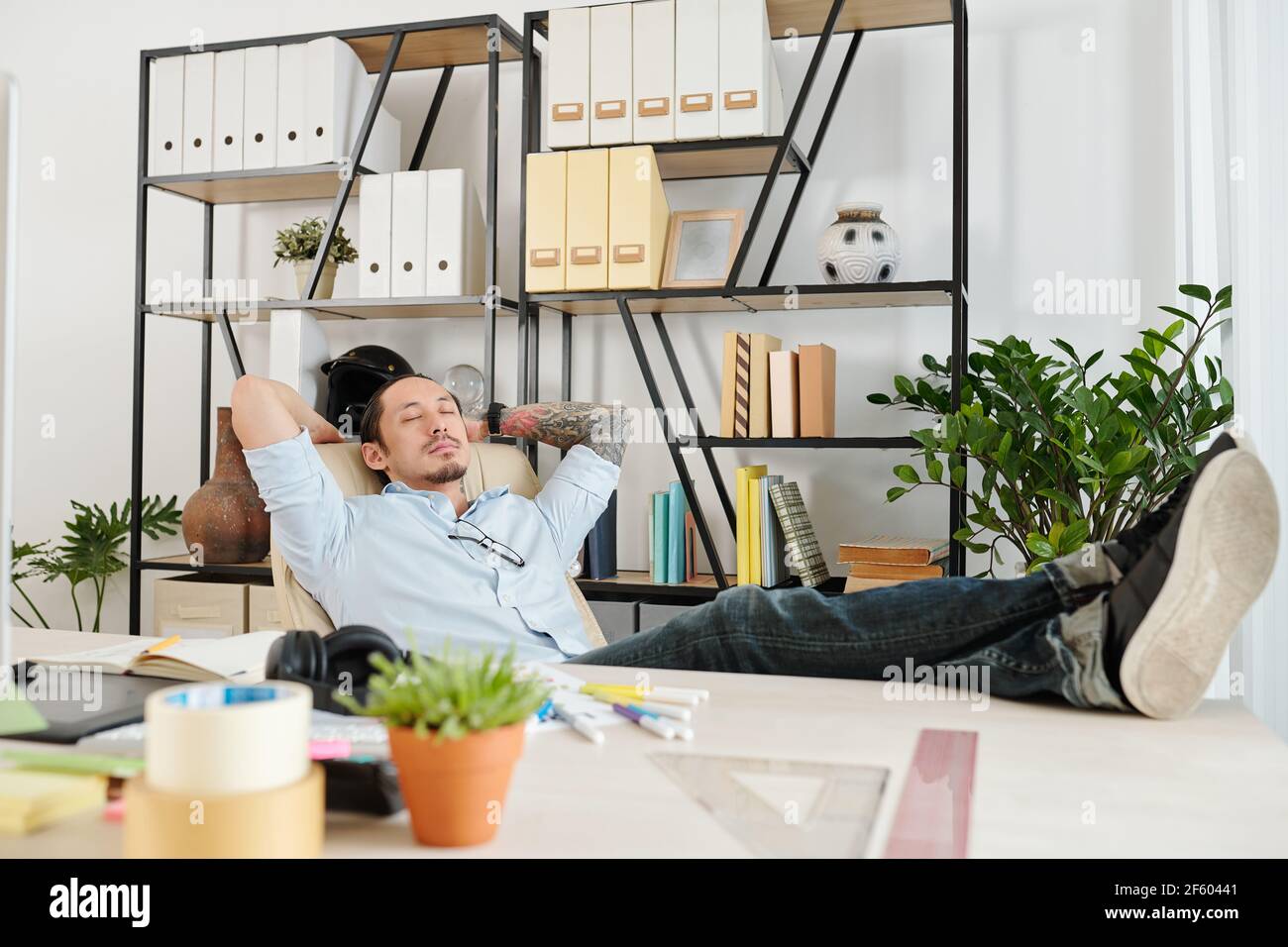 Graphic designer sleeping in his chair when enjoying short break after finishing work on big project Stock Photo