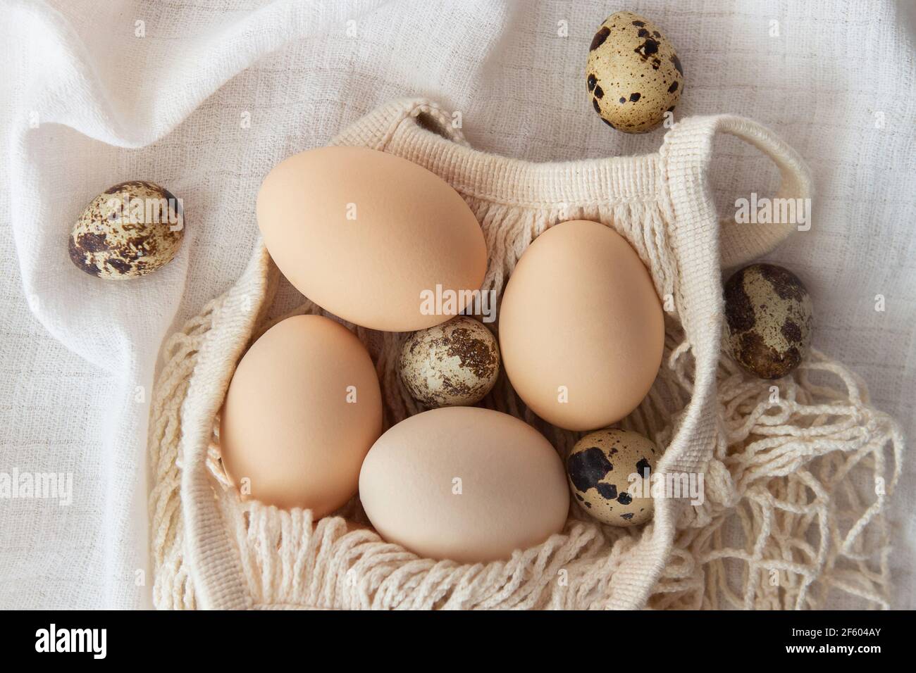 Chicken eggs in a string bag on white background, selective focus. Happy easter background. Stock Photo