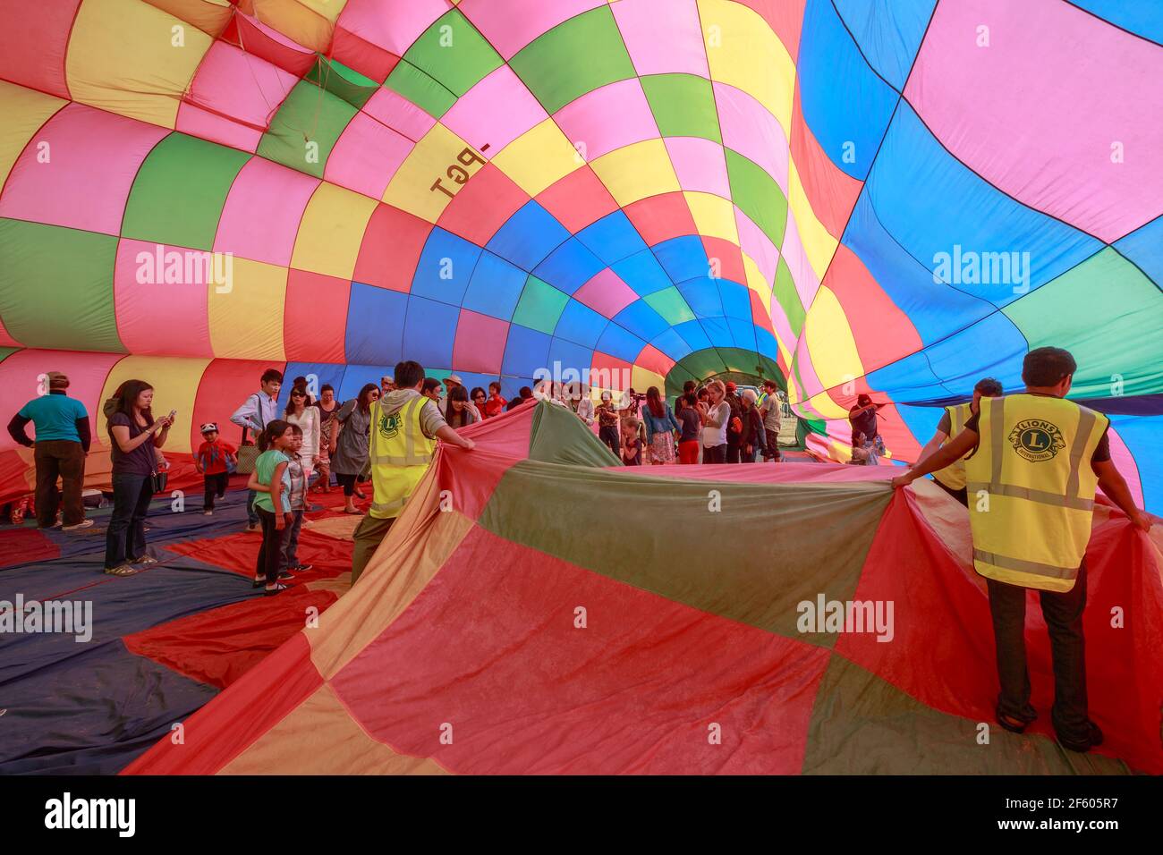 People inside the colorful envelope of a halfinflated hot air balloon