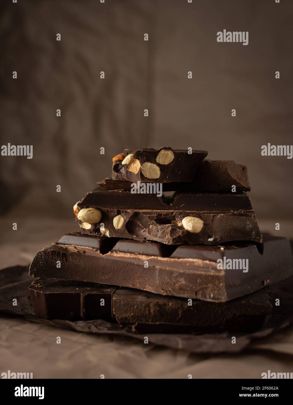 Dark chocolate with almonds and hazelnuts in a stack on brown background Stock Photo