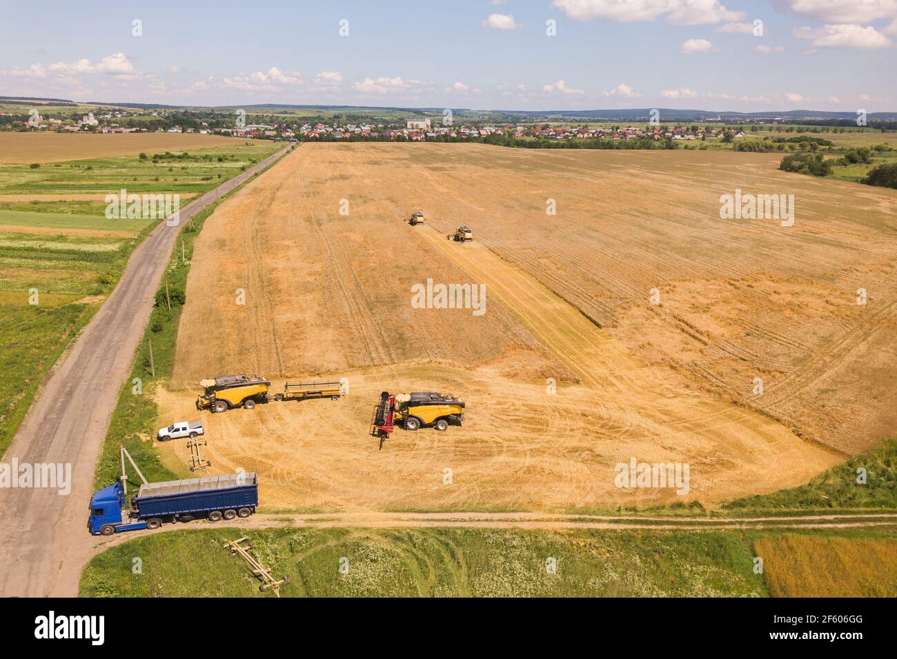 Aerial view of combine harvesters harvesting large yellow ripe wheat ...
