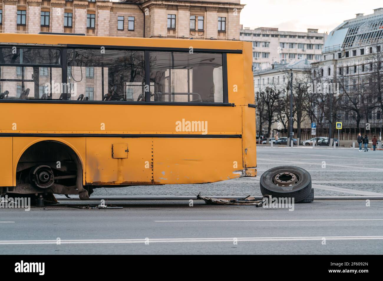 City bus with broken wheel stands on urban road. Stock Photo