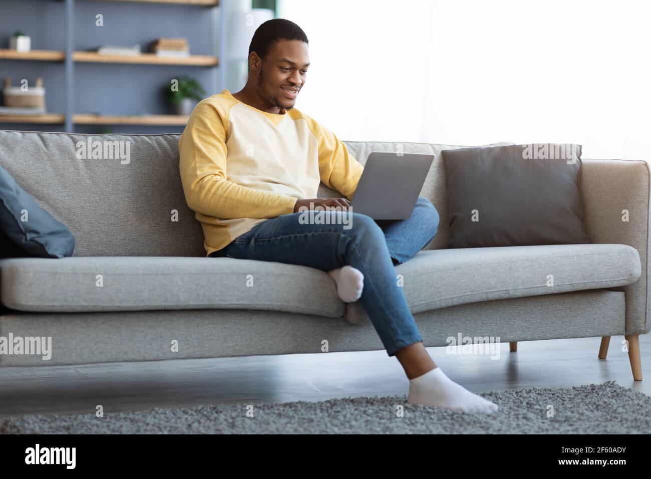 Black guy spending time at home, using laptop Stock Photo