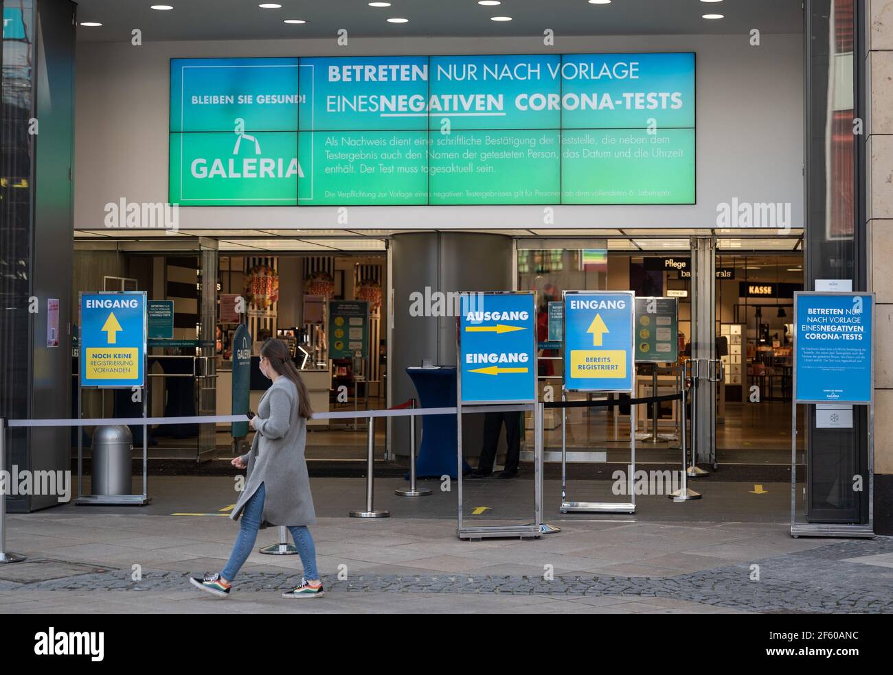 Dortmund, Germany. 29th Mar, 2021. A passer-by walks past the entrance of a Galeria Kaufhof store, in front of which a sign indicates that entry is only possible upon presentation of a 'negative Corona test'. A new Corona protection regulation comes into force in North Rhine-Westphalia. Credit: Bernd Thissen/dpa/Alamy Live News Stock Photo
