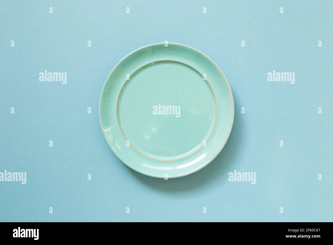 Empty ceramic round plate isolated on blue background. top view Stock Photo
