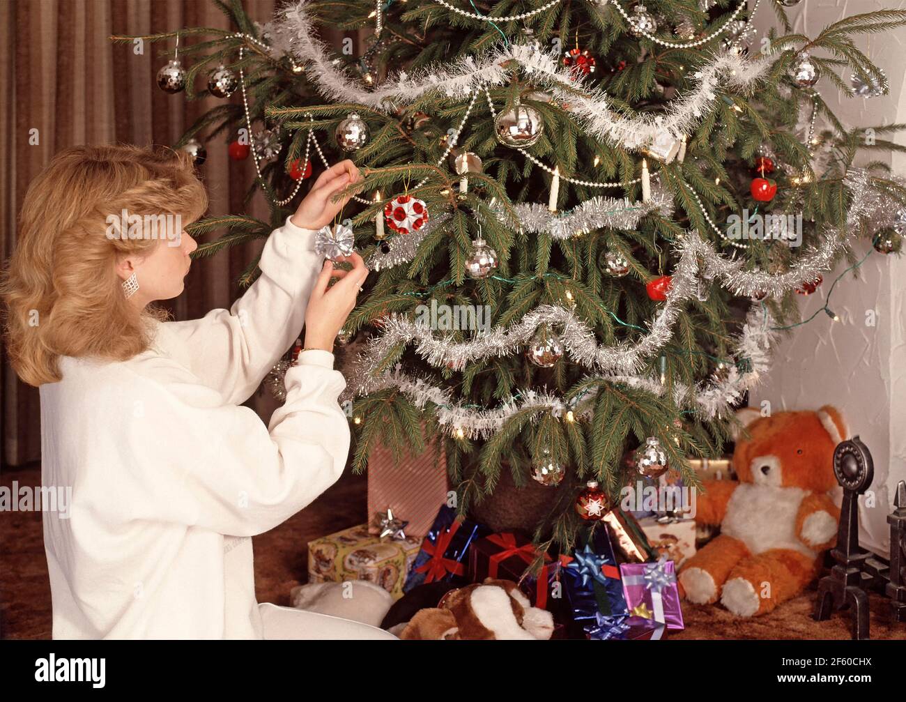 Young model released teenage school girl creating and setting up her own 1980s design for making a personal 1986 Christmas card to then get Dad to photograph it for her to print and send to her friends after decorating a real family Christmas Tree in the Living Room Lounge at home in England UK historical the way we were in an 80s archive lifestyle image Stock Photo