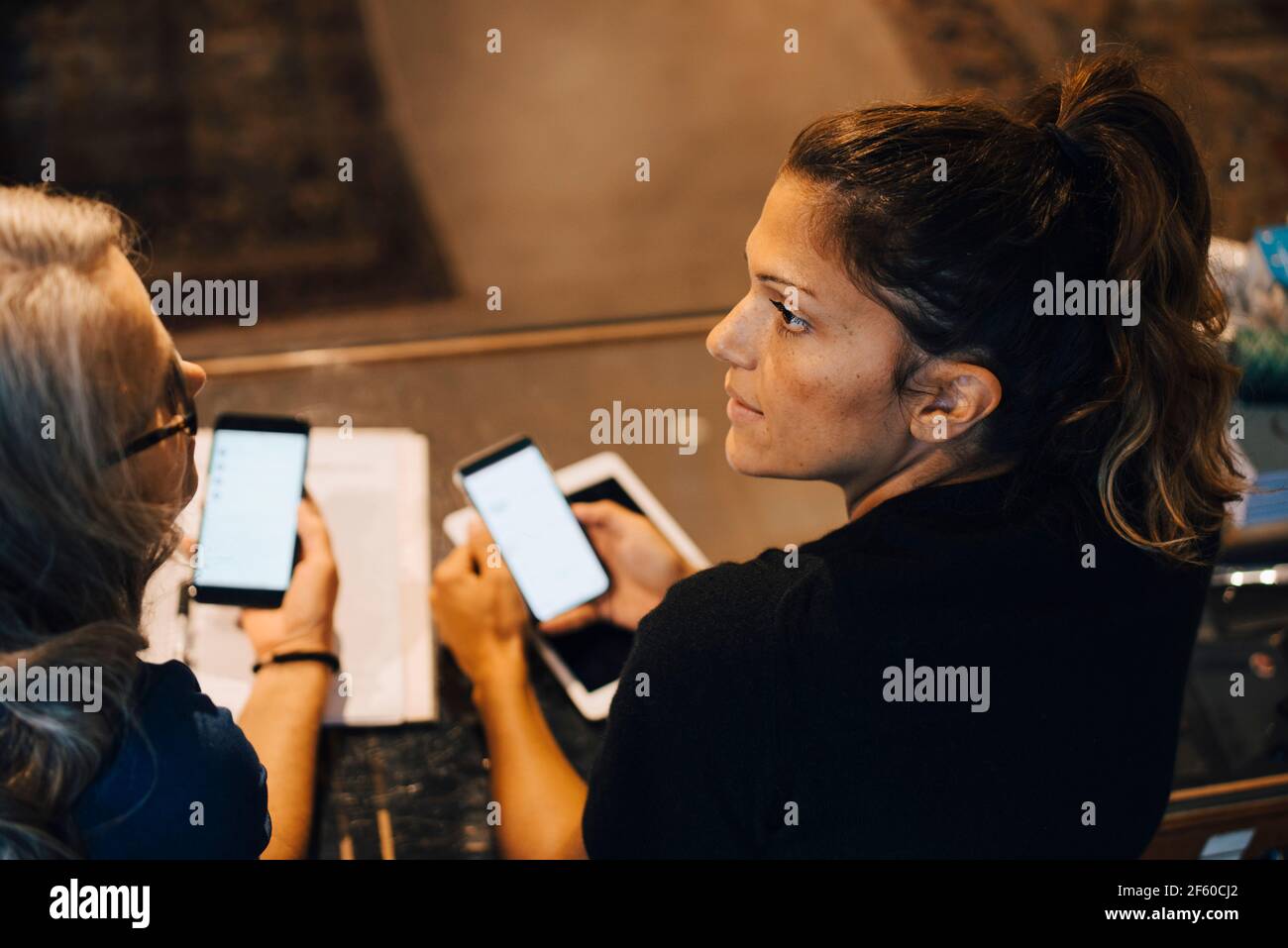Female colleagues using smart phone in retail store Stock Photo