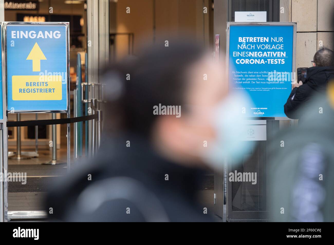 Dortmund, Germany. 29th Mar, 2021. A passer-by walks past the entrance of a Galeria Kaufhof store, in front of which a sign indicates that entry is only possible upon presentation of a negative Corona test. A new Corona protection regulation comes into force in North Rhine-Westphalia. Credit: Bernd Thissen/dpa/Alamy Live News Stock Photo