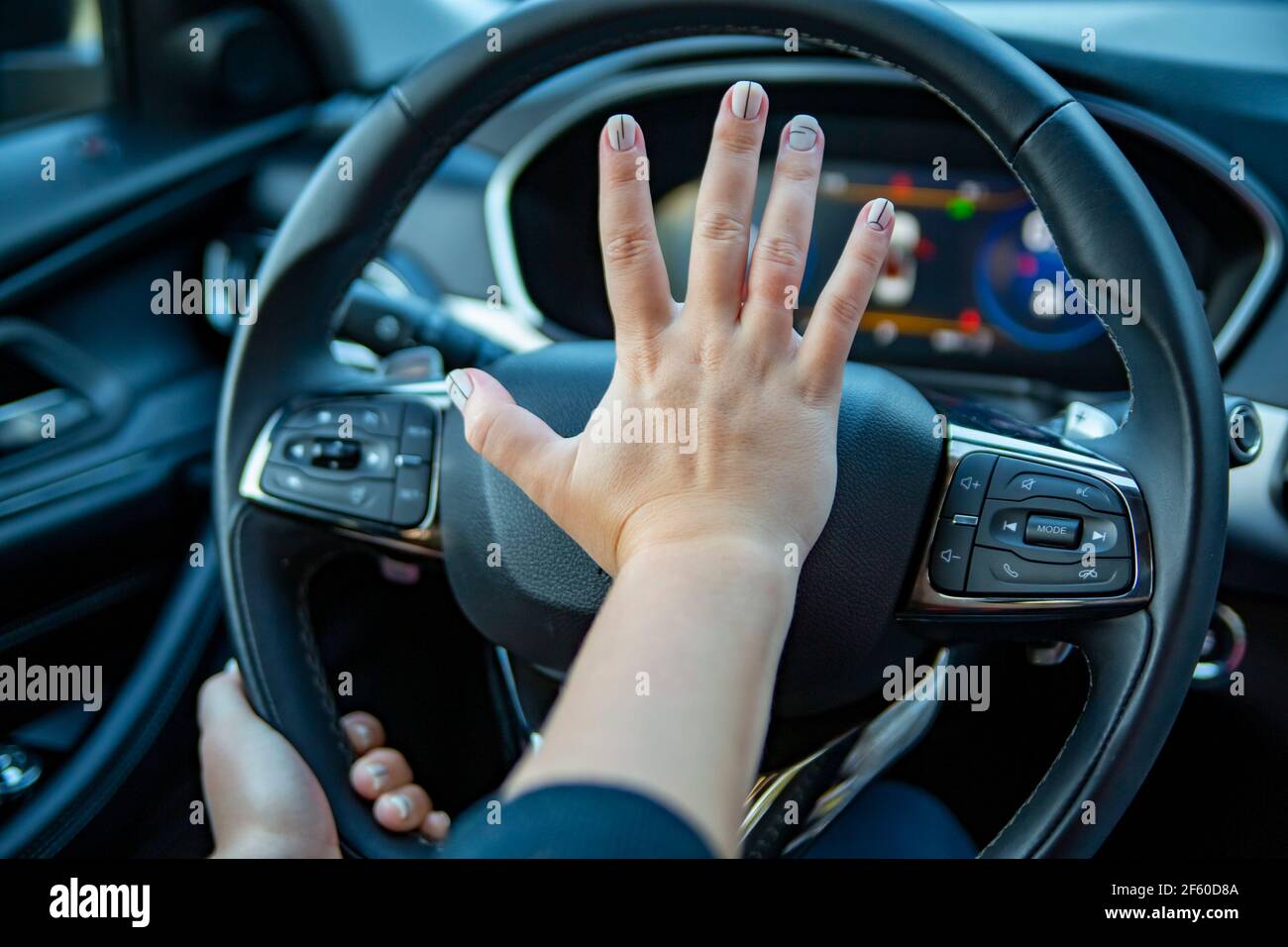 female hand presses the horn on the steering wheel of a modern car