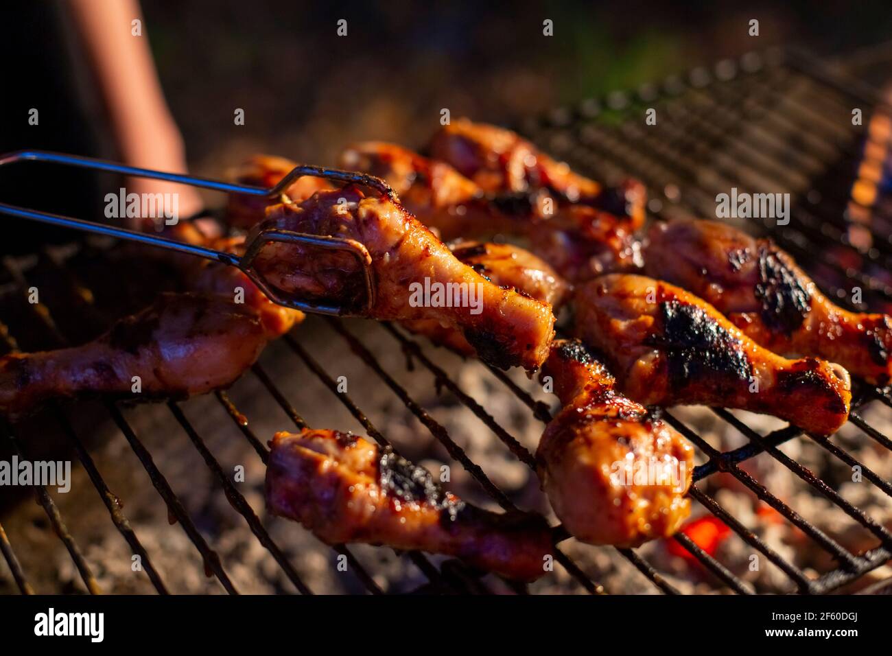 chicken drumsticks are grilled on a barbecue grill in the evening Stock