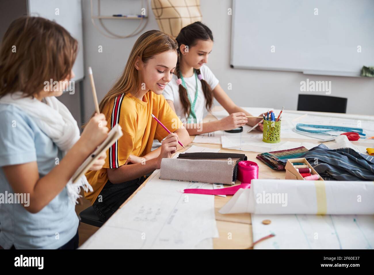 Joyful female children working in sewing workshop Stock Photo