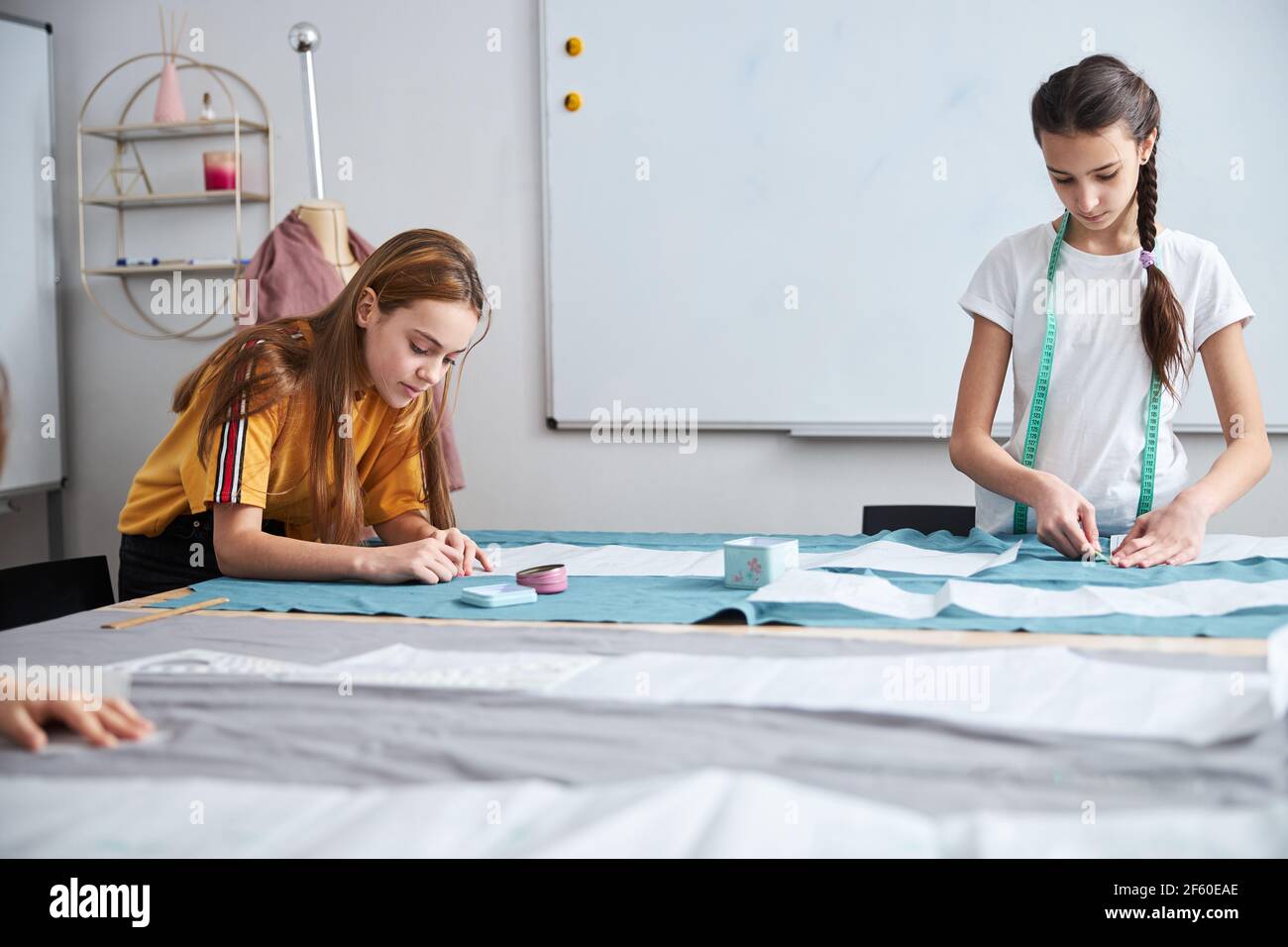 Adorable girls preparing fabric in sewing workshop Stock Photo