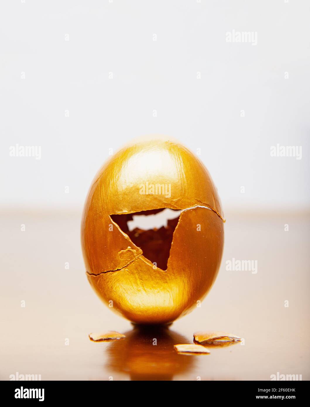 Golden egg with triangle hole placed on reflective table Stock Photo