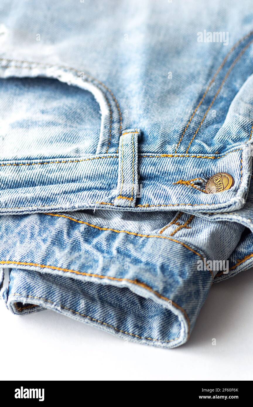 Blue jeans on a white background. The texture of the cotton fabric. Close up. Vertical crop. Stock Photo