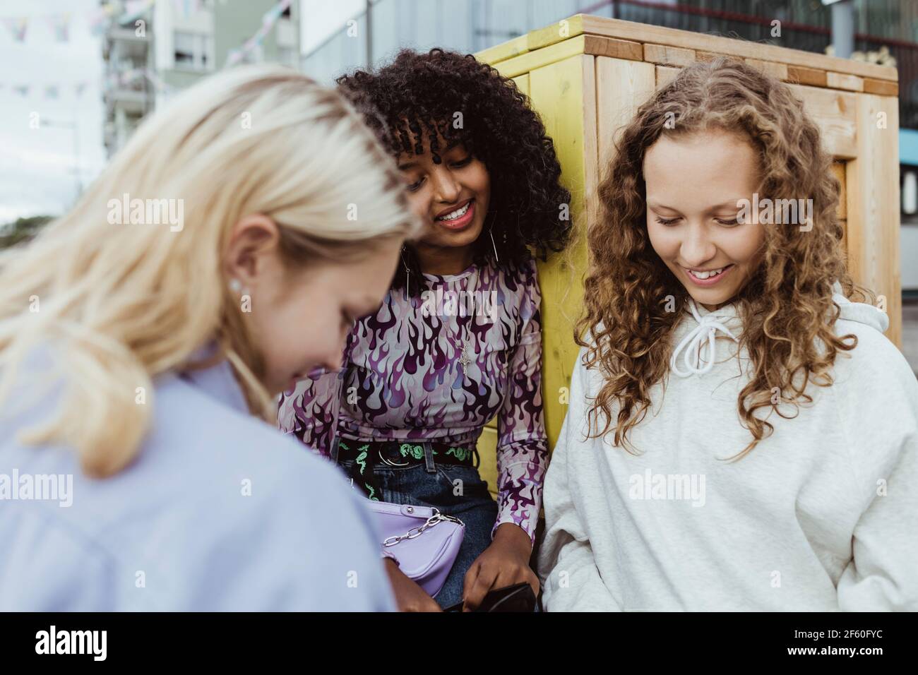 Smiling female friends looking down by box container outdoors Stock Photo