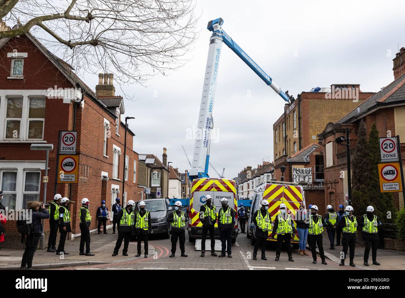 London, United Kingdom. 29th Mar, 2021. Bailiffs and police blockade Cavendish Road as a crane is used to access the roof of the police station. The police station had been occupied by squatters and autonomous activists under the name of ‘Not A Cop Shop’ for over a week, in opposition to the new ‘Police, Crime, Sentencing, and Courts Bill’ and femicide. Cavendish Road Police Station, Clapham, London, United Kingdom. Credit: Joshua Windsor/Alamy Live News. Stock Photo