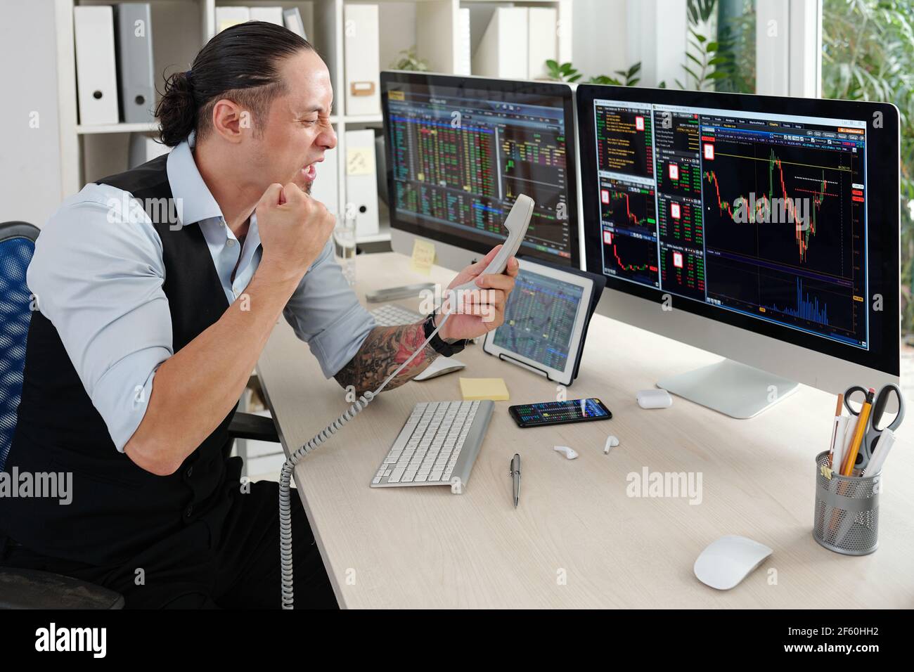 Emotional angry trader screaming in telephone receiver after loosing money in stock market Stock Photo