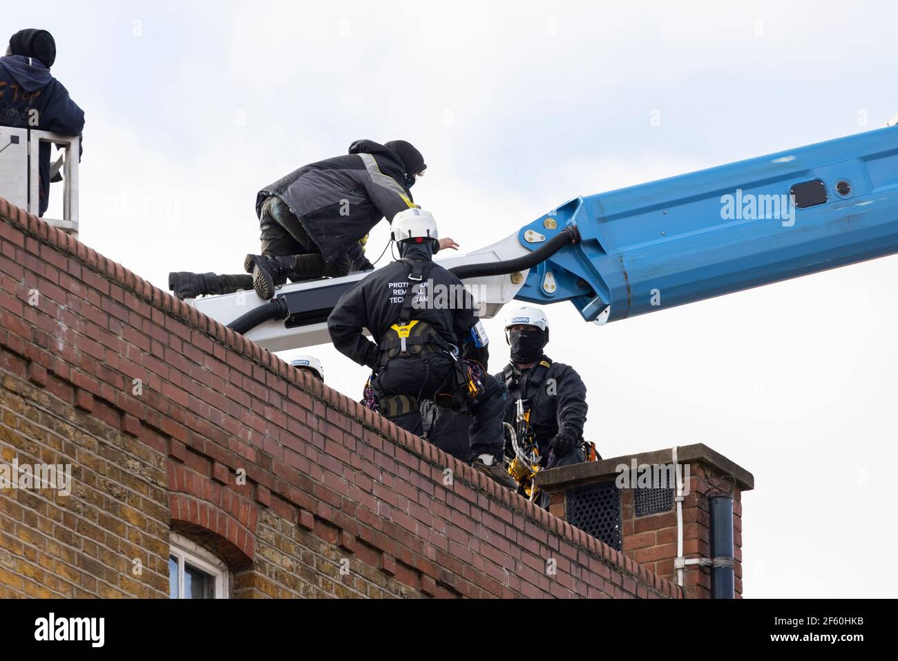 London, United Kingdom. 29th Mar, 2021. A protester sits on top of a crane used to access protesters on the rooftop. The police station had been occupied by squatters and autonomous activists under the name of ‘Not A Cop Shop’ for over a week, in opposition to the new ‘Police, Crime, Sentencing, and Courts Bill’ and femicide. Cavendish Road Police Station, Clapham, London, United Kingdom. Credit: Joshua Windsor/Alamy Live News. Stock Photo