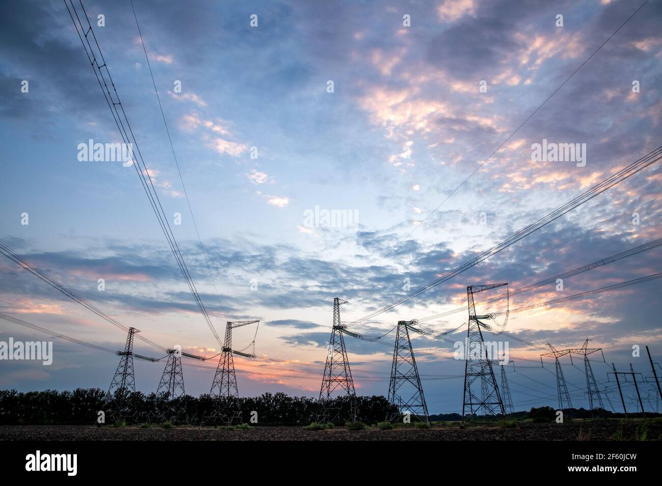 Electrical pylons and high voltage power lines at sunset background ...