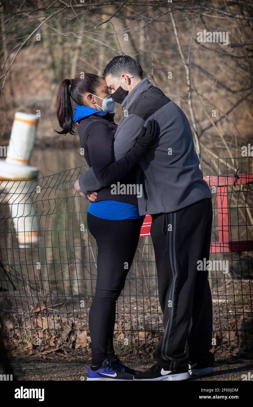 LOVE IN THE AGE OF COVID. A couple go head to head & mask to mask in a park in Queens, New York City. Stock Photo