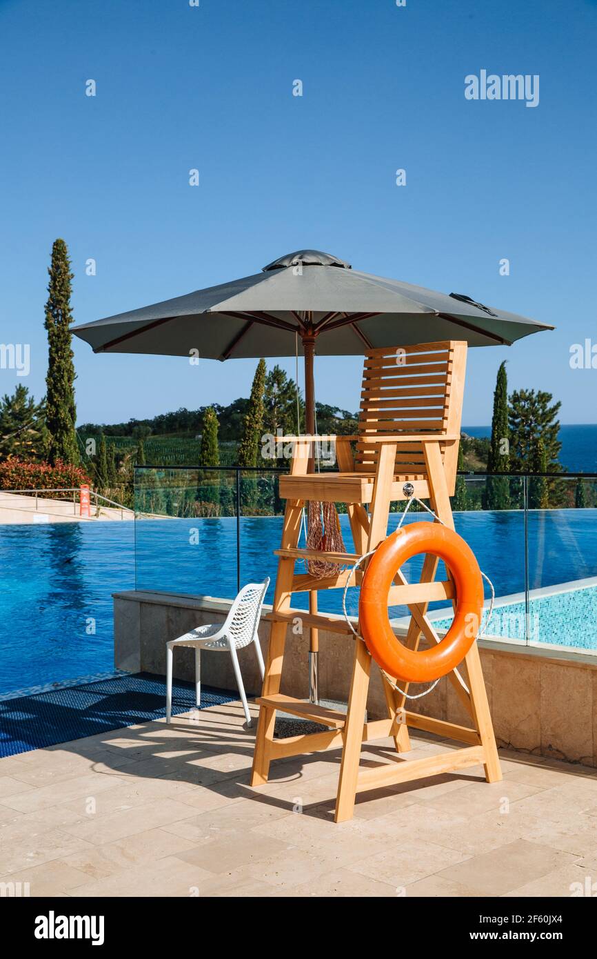 The lifeguard's post is under a sun umbrella. A life preserver hangs nearby. Water safety concept. Stock Photo