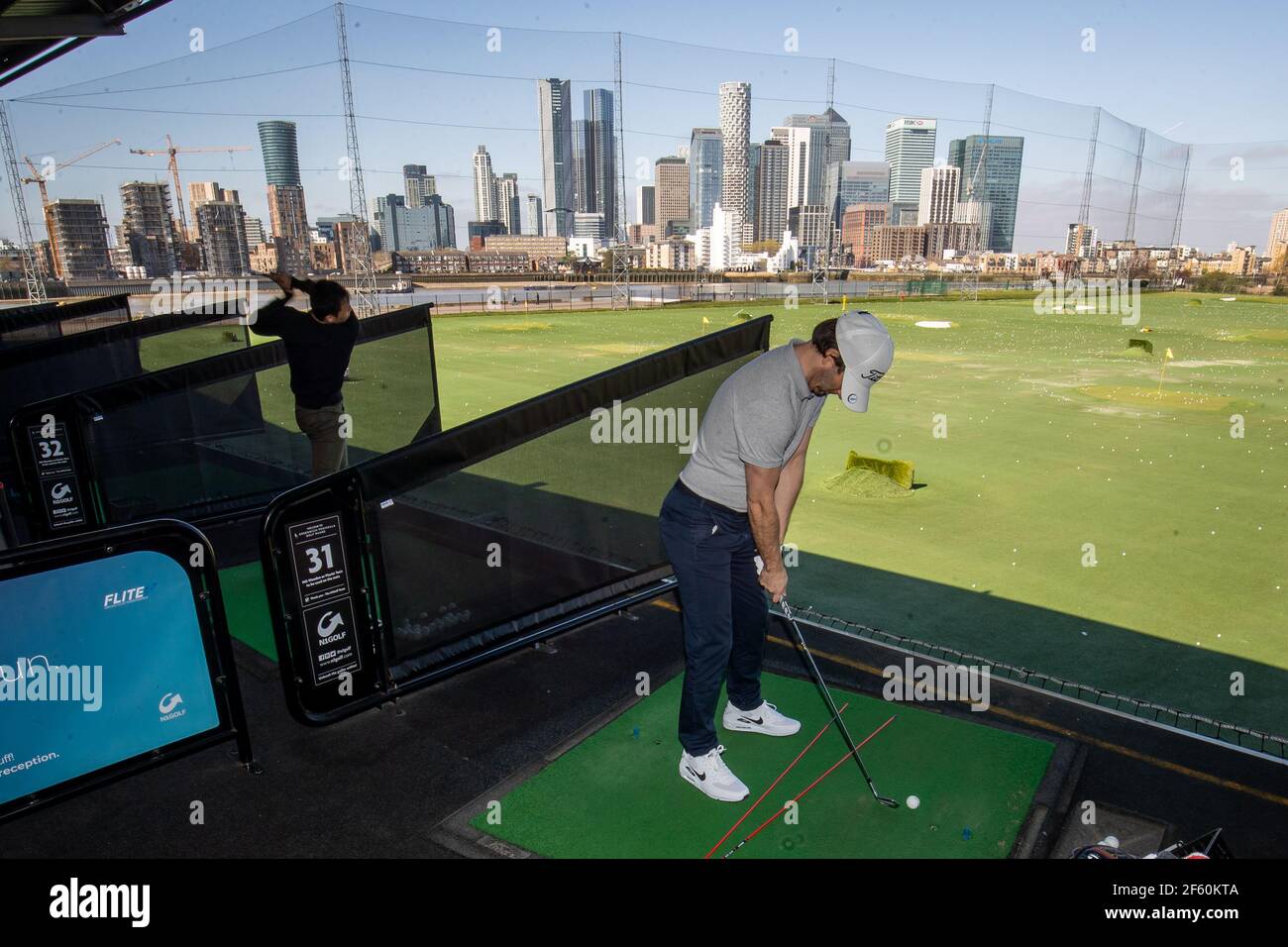A golfer hits a ball with a view of Canary Wharf on the driving range at  Greenwich Peninsula Driving Range, London, following the easing of  England's lockdown to allow far greater freedom