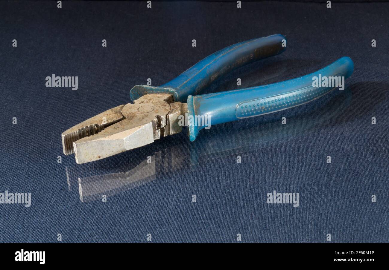 Iron pliers lie on a table with a reflection. Locksmith tools on a black background Stock Photo