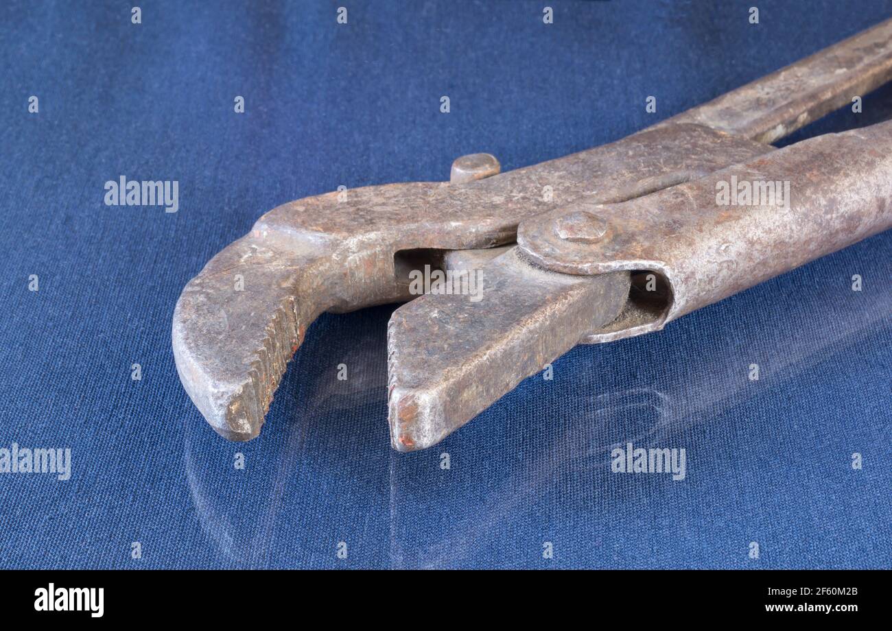 A rusty wrench on a table with a reflection. Locksmith tools on a blue background Stock Photo
