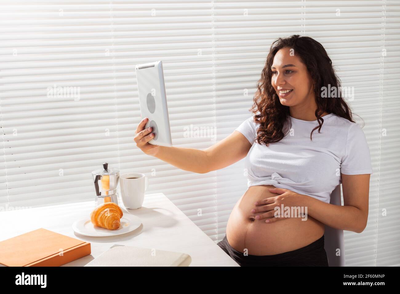 Happy pregnant young beautiful woman talking to mom using video call during  morning breakfast. Concept of communication and positive attitude during  Stock Photo - Alamy