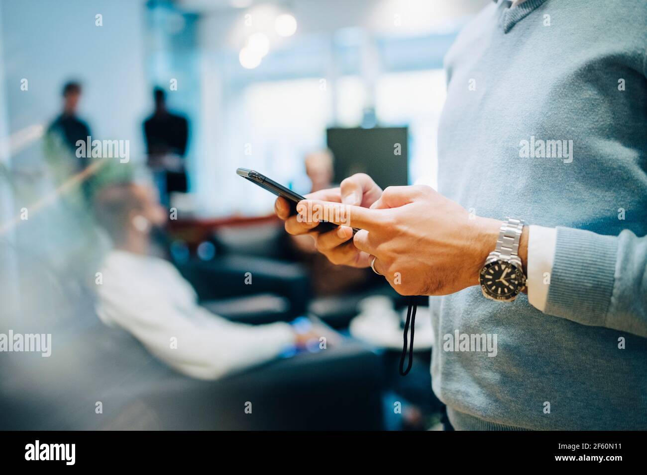 Midsection of businessman using smart phone at office Stock Photo