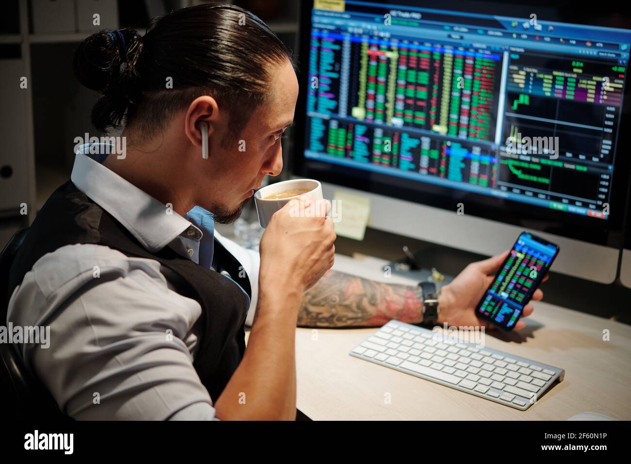 Professional trader having coffe break and monitoring open positions to ensure that he will have enough time to make a profit before the markets close Stock Photo