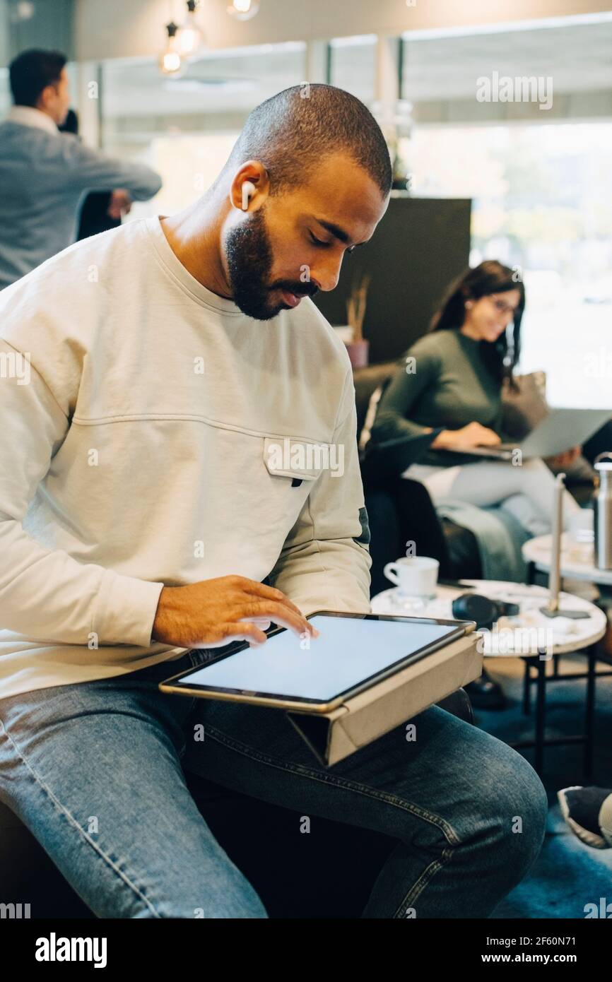 Male entrepreneur using digital tablet while working with colleagues in office Stock Photo