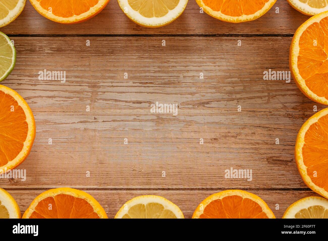 Oranges,limes and lemons slides on wooden table view from above.Beautiful background with fresh fruit half cut.Healthy eating vitamin C.Summer tropic Stock Photo