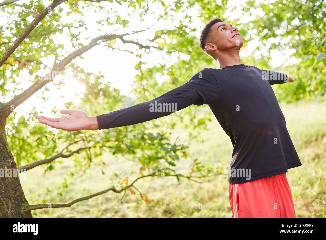 Young man with arms outstretched doing breathing exercise for health and stress relief Stock Photo