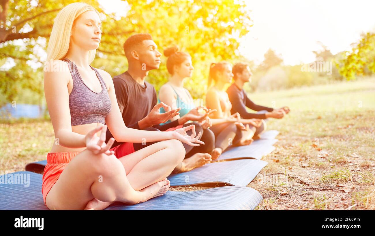 Group of people doing yoga in class together as fitness training in nature Stock Photo
