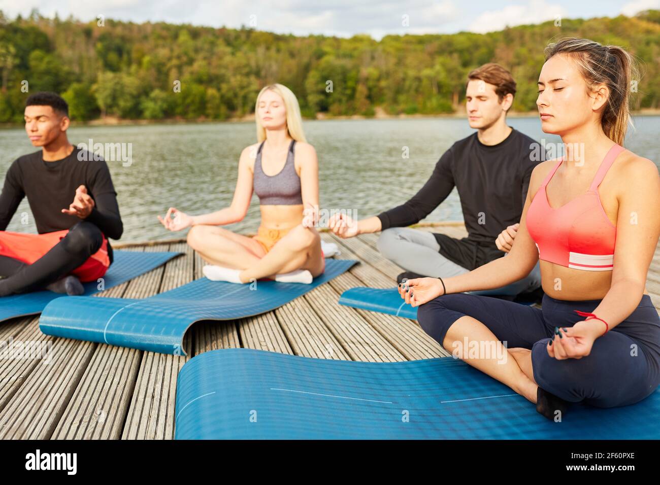 Group of young people doing yoga for health and relaxation in summer by the lake Stock Photo