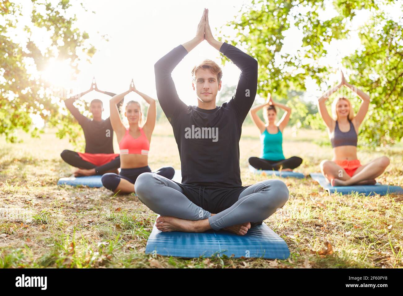 Group of friends doing a yoga meditation for balance and inner peace in nature Stock Photo