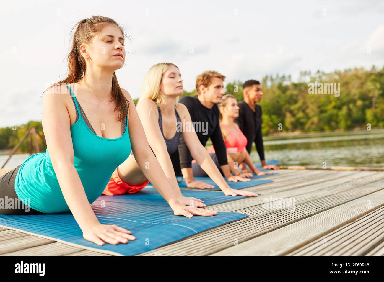 Young people doing a yoga exercise for health and relaxation in the wellness course Stock Photo