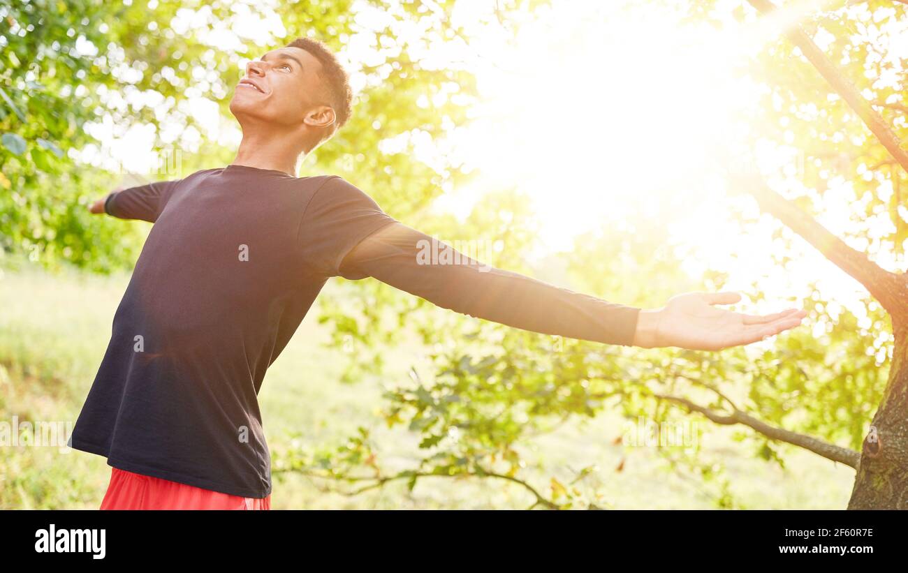 Young african man doing breathing exercise for relaxation in nature in summer Stock Photo