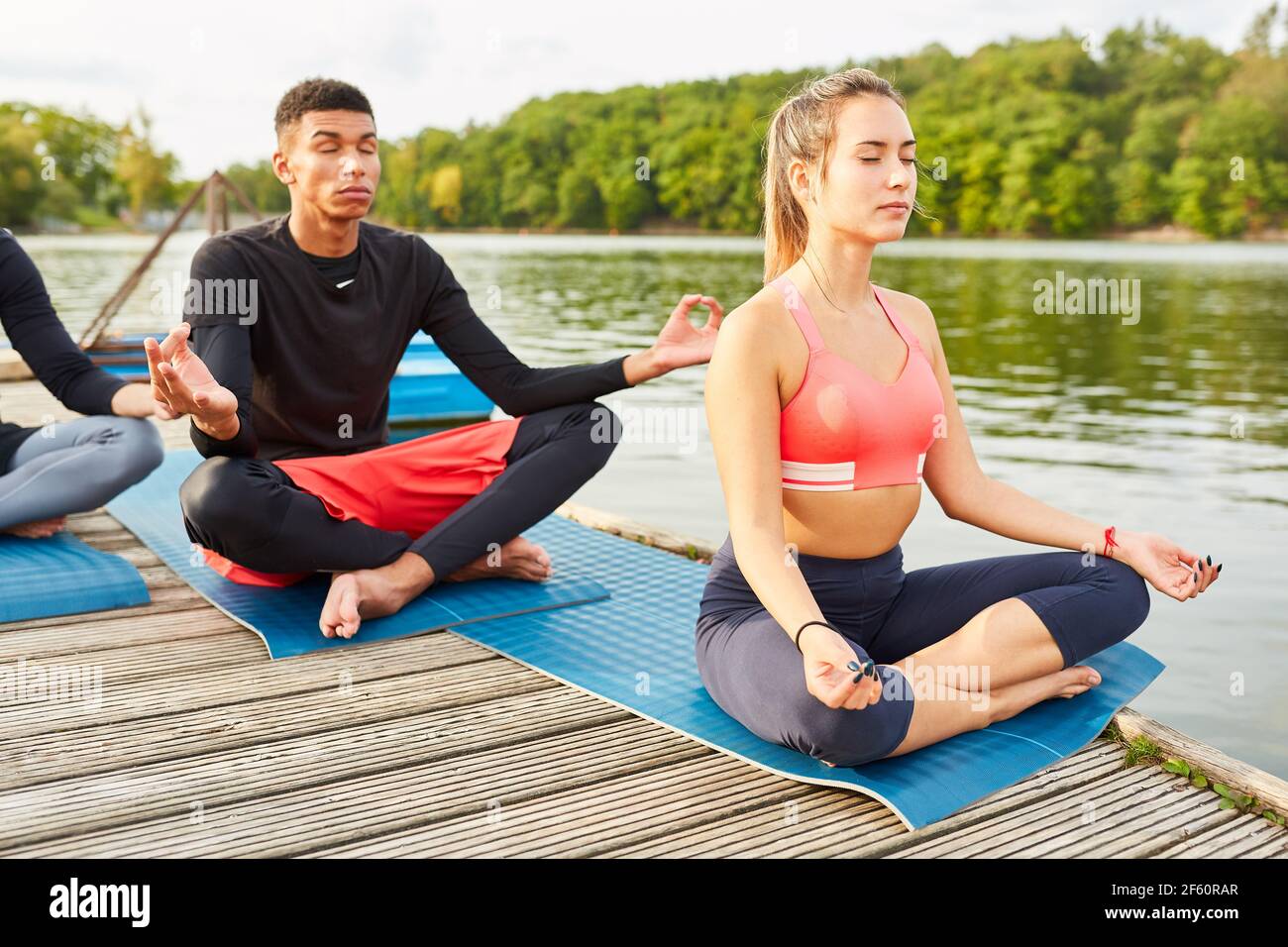 People do yoga meditation for relaxation and enlightenment in nature by the lake Stock Photo
