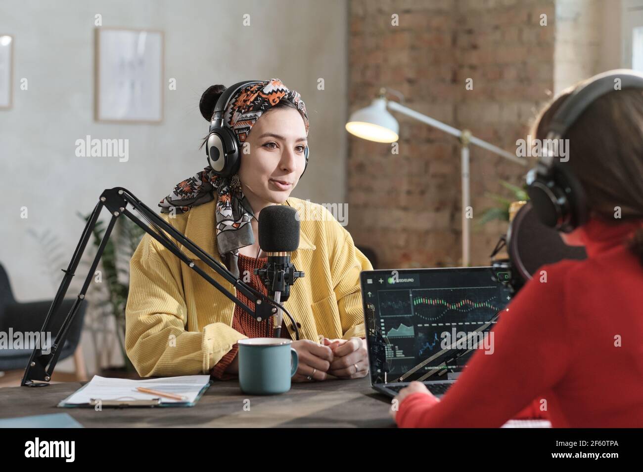 Female radio dj in headphones speaking in microphone and interviewing a