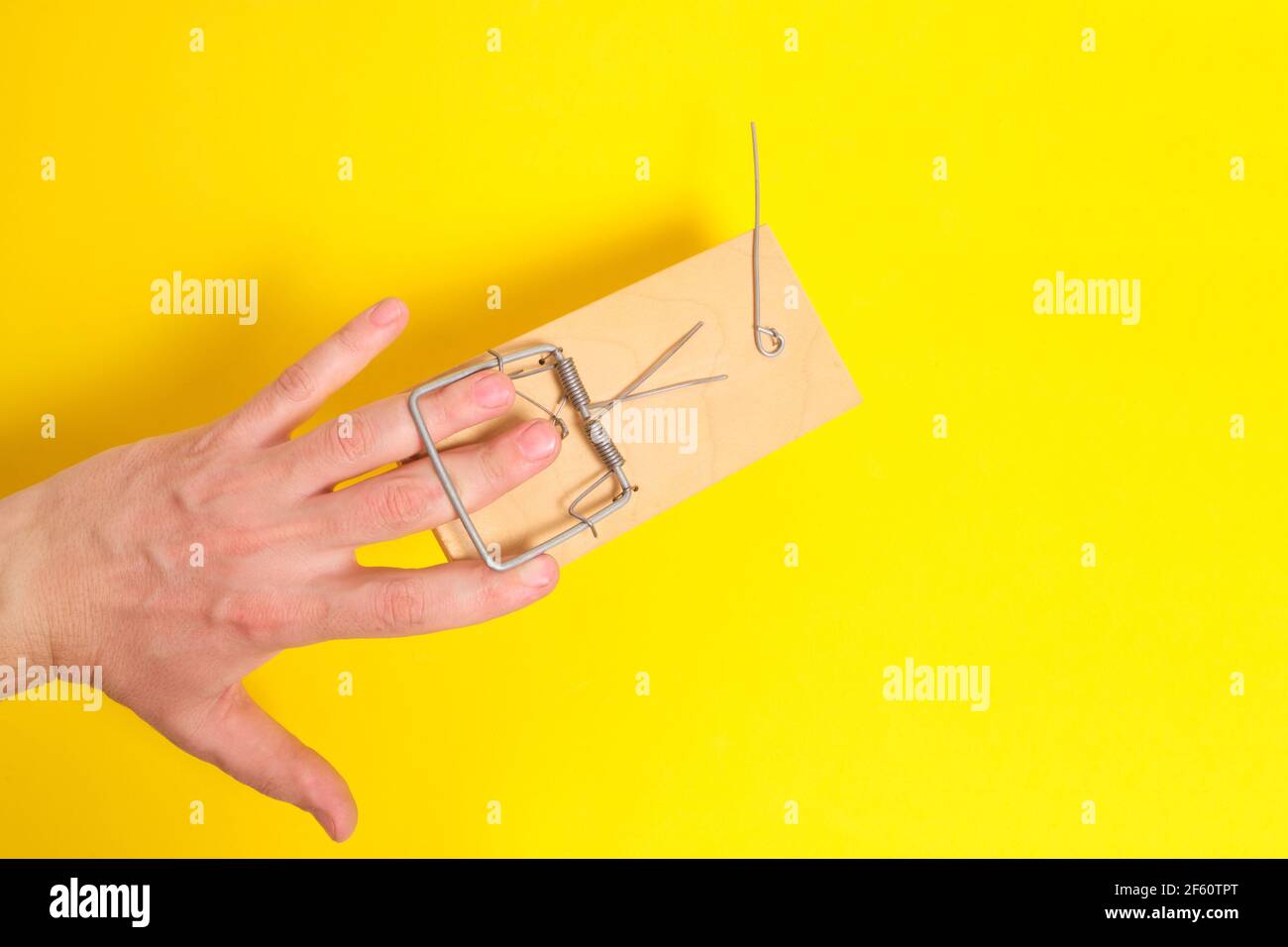 Man hand was caught in a mousetrap on a yellow background.Concept, risks, and failures Stock Photo