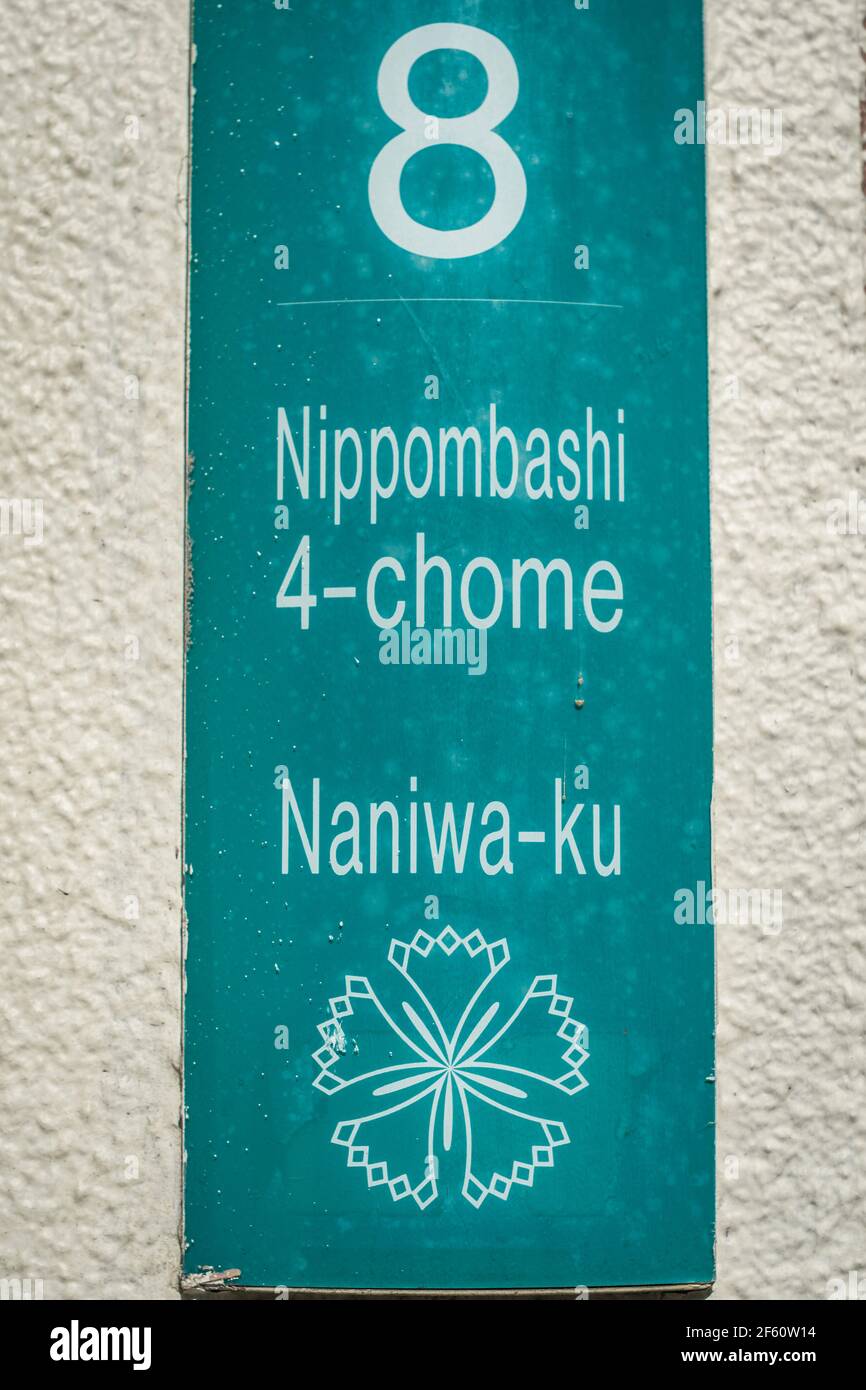 Close up detail of a green metal street name sign sign on a white wall in Osaka, Japan indicating Nipponbashi (Nippombashi) 4-Chome in Naniwa-ku Stock Photo
