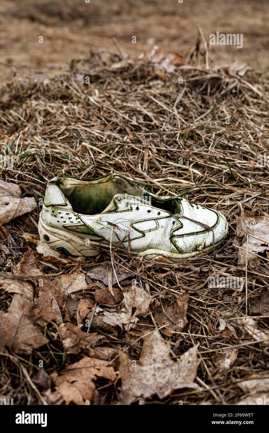 old-torn-sneakers-in-dirty-grass-2F60WET.jpg
