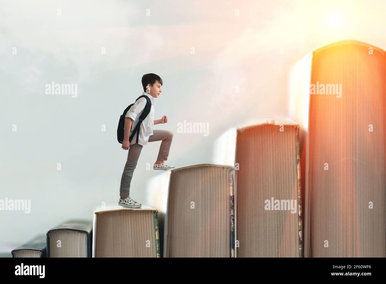 Child climbing stairs made of on sky background. Education or hard study concept. Soft focus Stock Photo