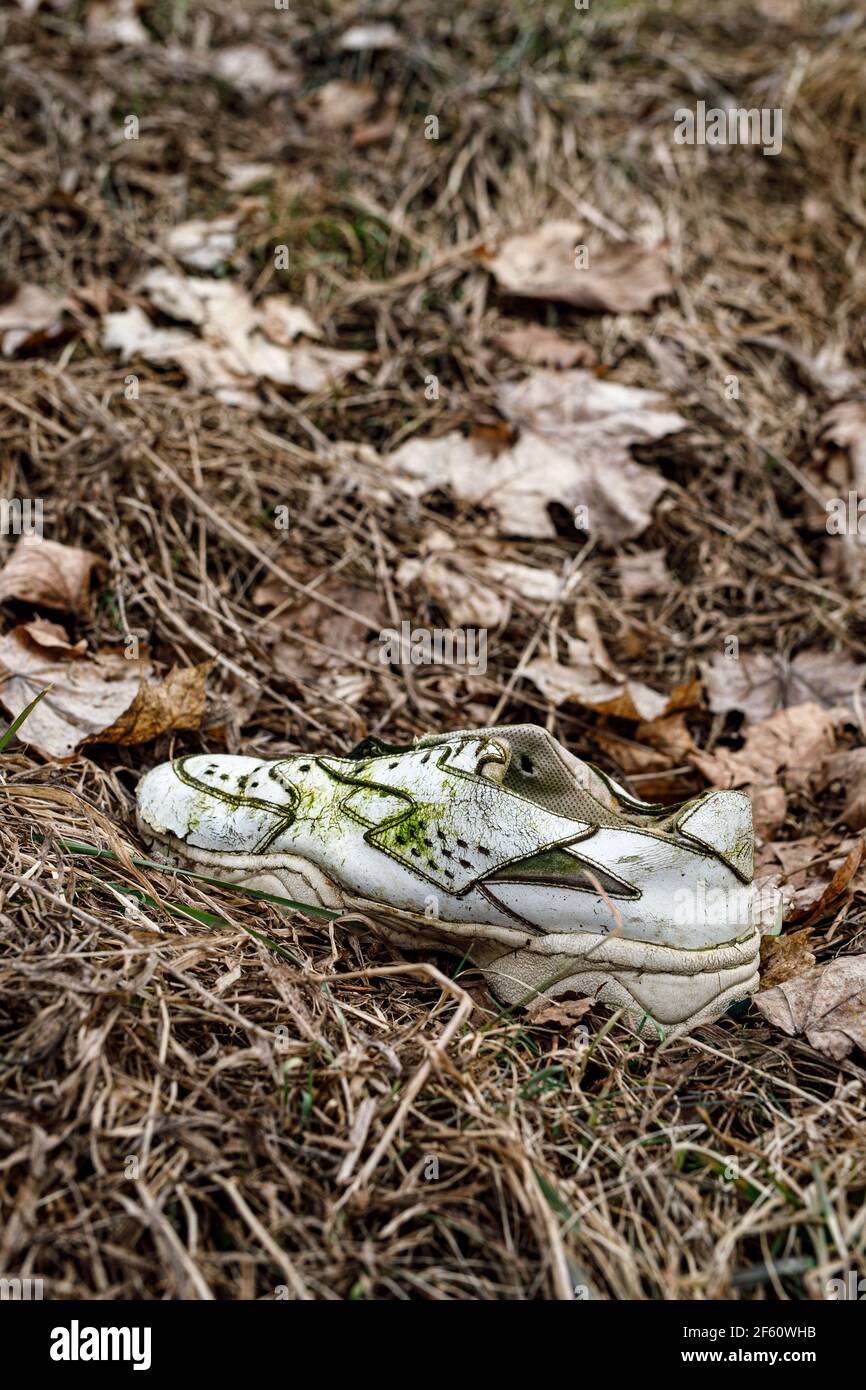 Old torn sneakers in dirty grass Stock Photo